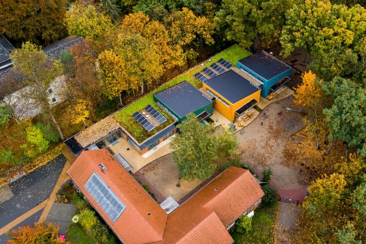 Erweiterungsbau der Kita Teltow aus der Luft mit begrüntem Dach zwischen Herbstbäumen