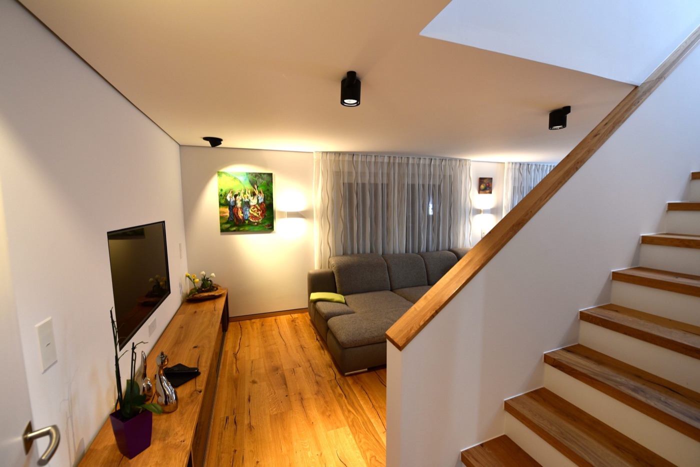 Holzhaus innen: Wohnraum mit Holztreppe, Holzboden und Sideboard aus Massivholz im Musterhaus „Felix“
